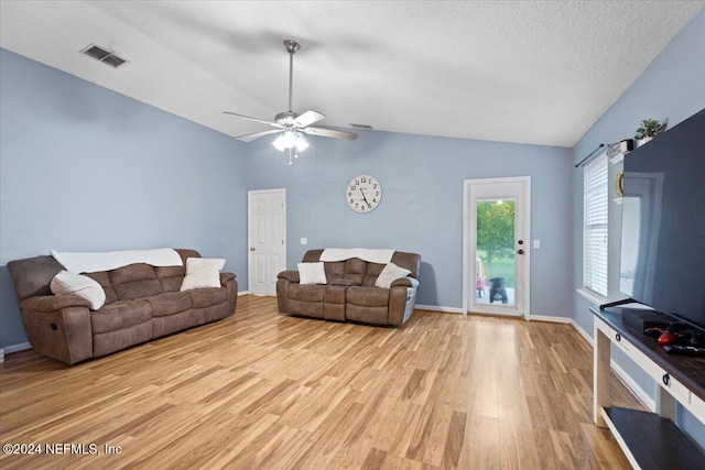 living room with a textured ceiling, light hardwood / wood-style floors, vaulted ceiling, and ceiling fan