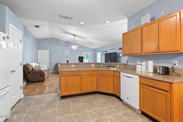 kitchen featuring kitchen peninsula, white appliances, vaulted ceiling, ceiling fan, and sink