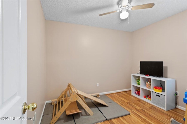 game room featuring a textured ceiling, hardwood / wood-style flooring, and ceiling fan