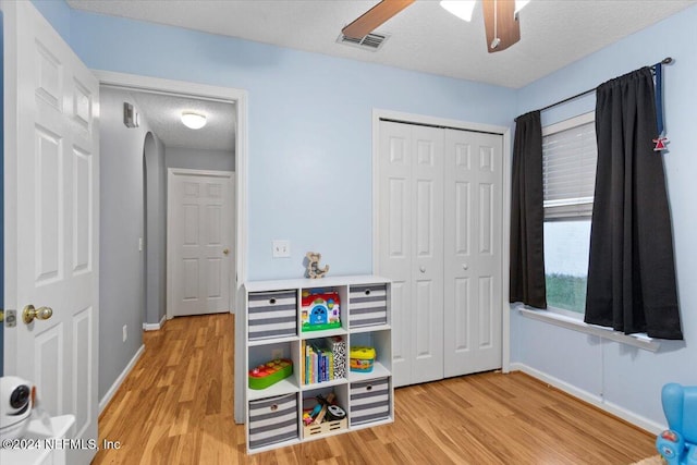 playroom with a textured ceiling, light hardwood / wood-style flooring, and ceiling fan