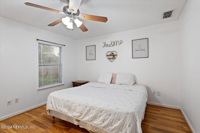 bedroom with ceiling fan, hardwood / wood-style floors, and a textured ceiling