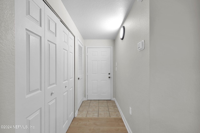 hall with light hardwood / wood-style flooring and a textured ceiling