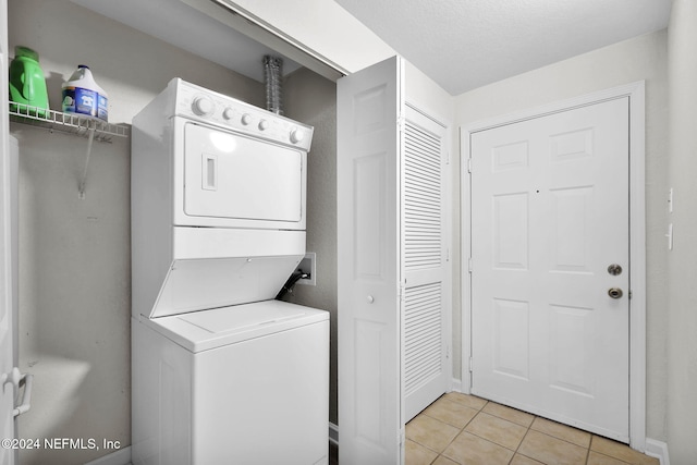 clothes washing area featuring stacked washer and clothes dryer and light tile patterned flooring