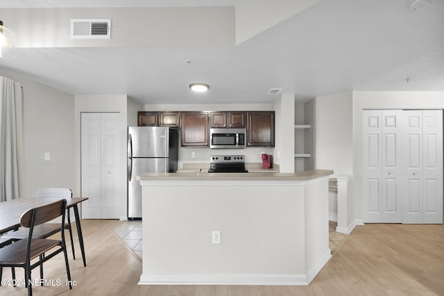 kitchen featuring an island with sink, appliances with stainless steel finishes, and light hardwood / wood-style flooring