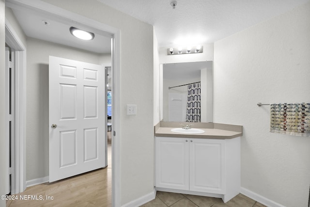 bathroom featuring a shower with shower curtain, vanity, and a textured ceiling