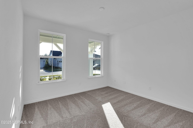 carpeted spare room with baseboards and plenty of natural light