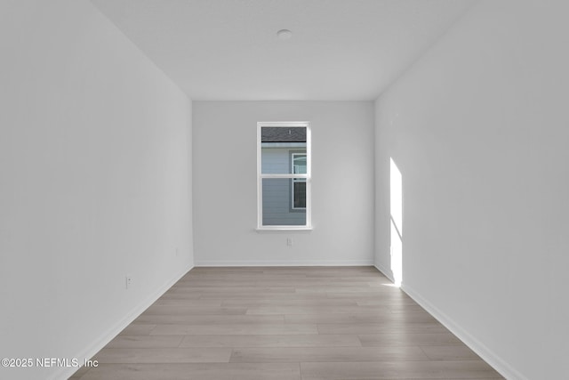 empty room featuring light wood-type flooring and baseboards