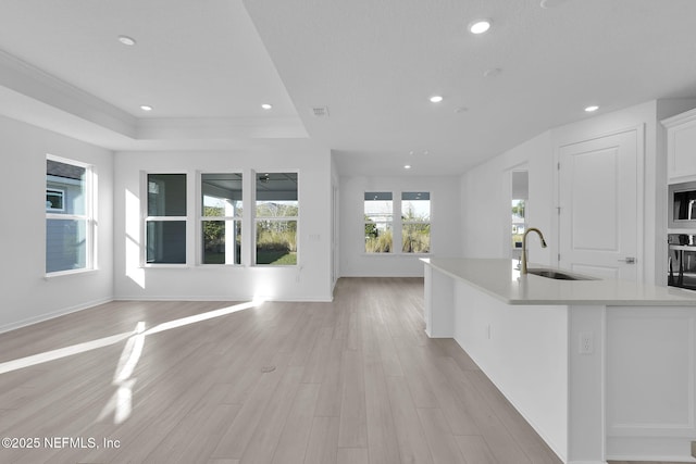 kitchen featuring a sink, stainless steel microwave, black oven, open floor plan, and light countertops