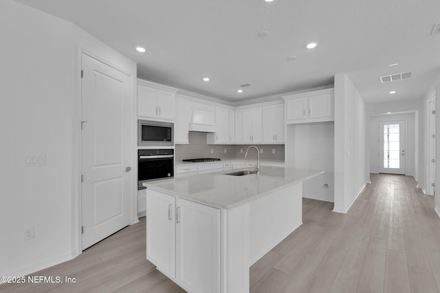 kitchen featuring oven, built in microwave, custom exhaust hood, gas cooktop, and a sink