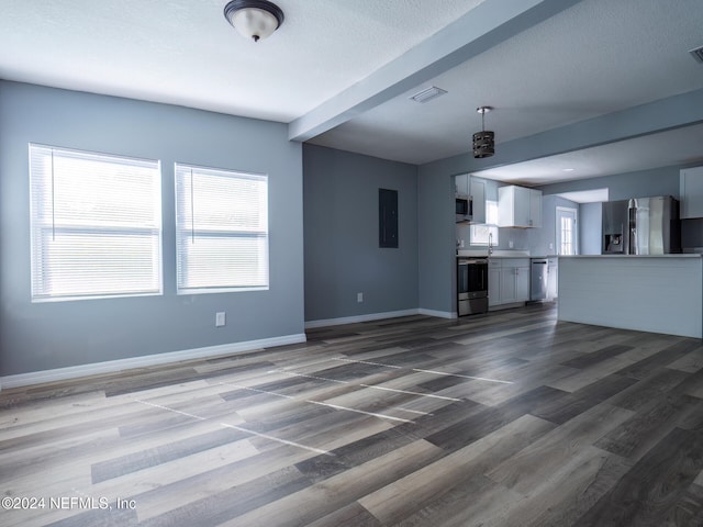 unfurnished living room featuring beam ceiling and dark hardwood / wood-style floors