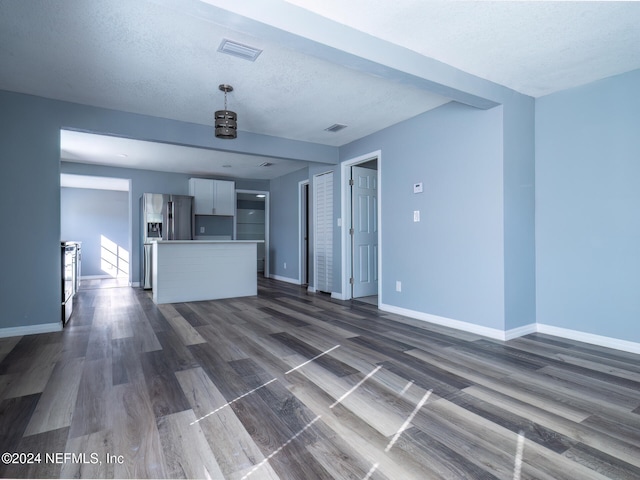 unfurnished living room featuring a textured ceiling and dark wood-type flooring