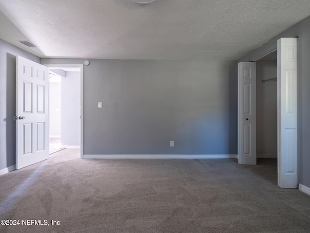 unfurnished room featuring carpet and a textured ceiling