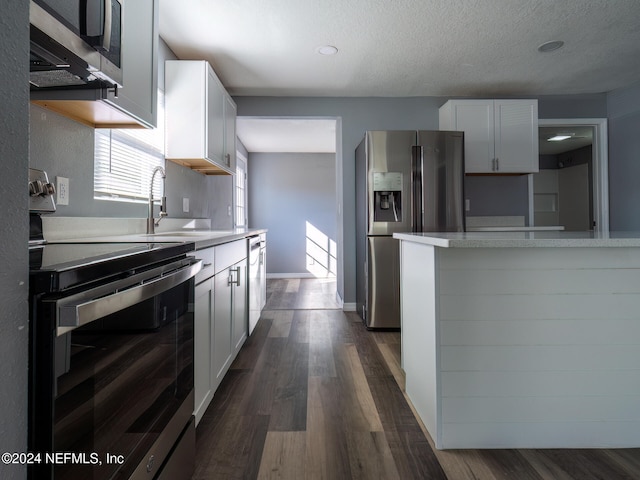 kitchen featuring white cabinets, appliances with stainless steel finishes, a textured ceiling, and dark hardwood / wood-style floors