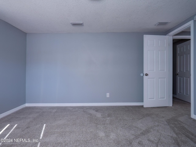 unfurnished room with a textured ceiling and carpet floors