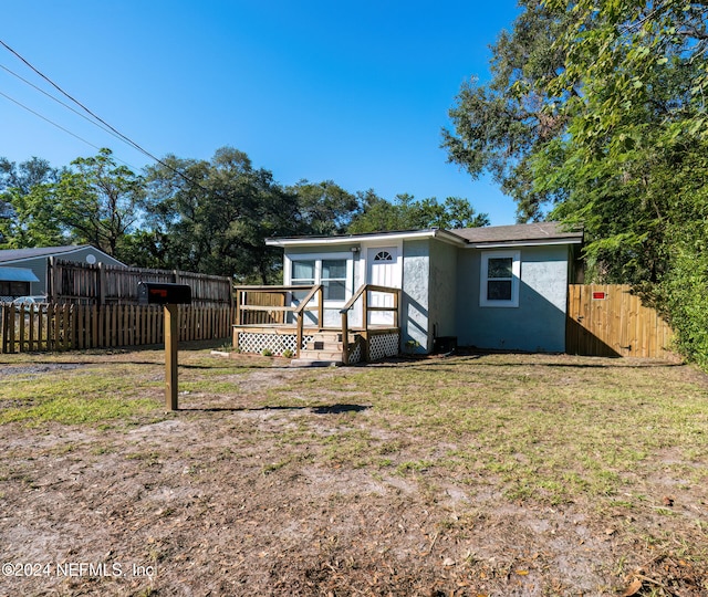 view of front of home with a front yard and a wooden deck