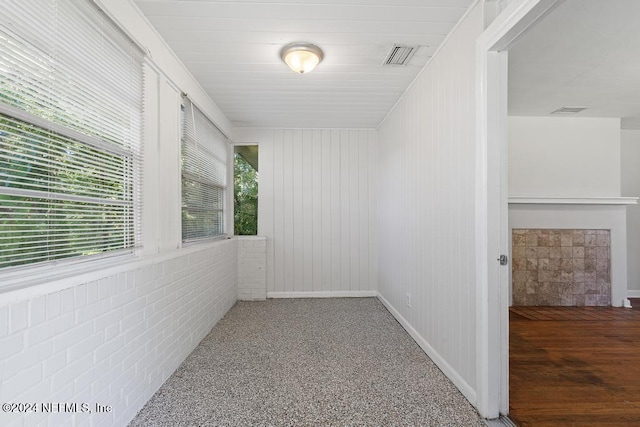 empty room featuring hardwood / wood-style flooring and brick wall