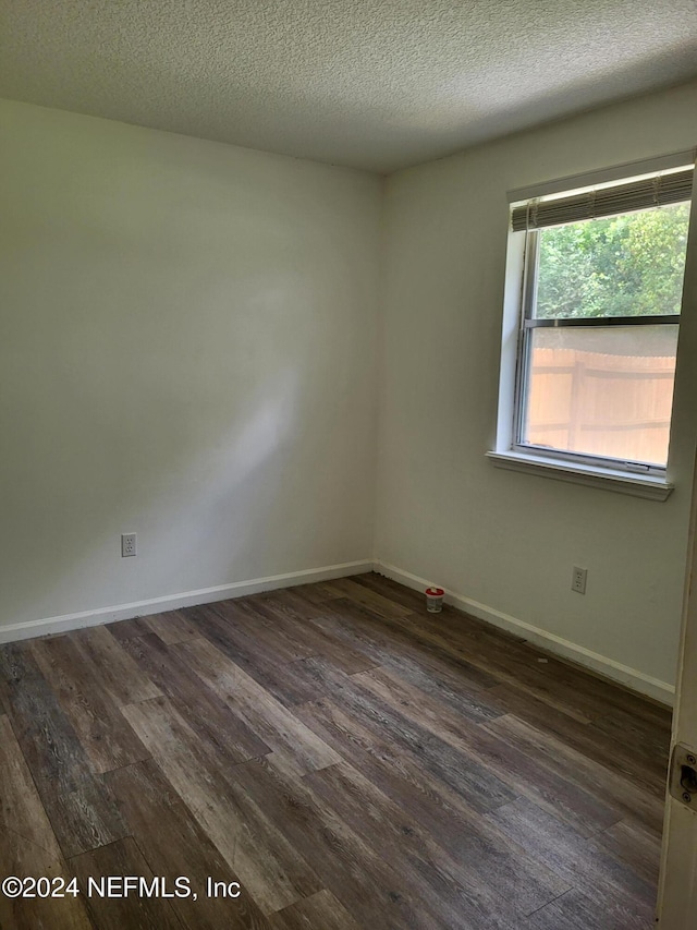 empty room featuring a textured ceiling and dark wood-type flooring