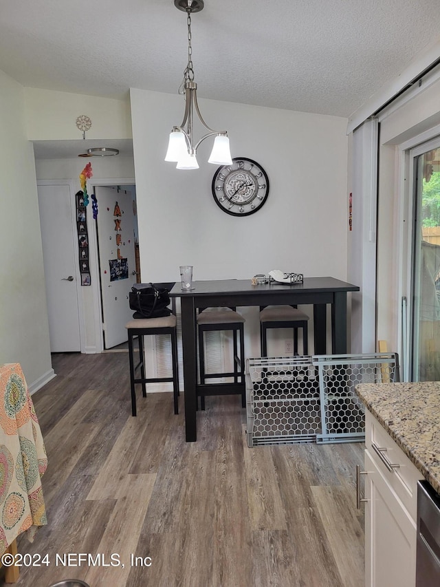 dining space with vaulted ceiling, dark hardwood / wood-style flooring, a textured ceiling, and an inviting chandelier