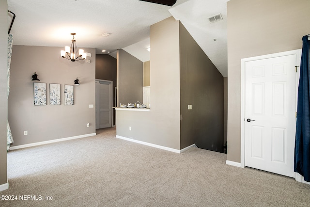 carpeted empty room featuring vaulted ceiling and an inviting chandelier