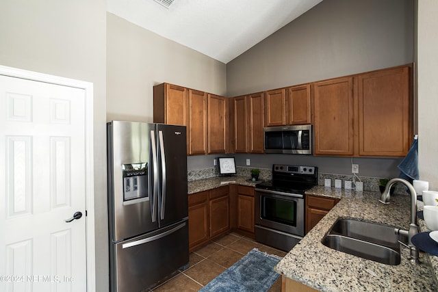 kitchen with light stone countertops, sink, dark tile patterned floors, high vaulted ceiling, and appliances with stainless steel finishes