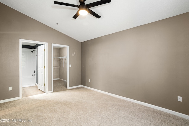 unfurnished bedroom featuring connected bathroom, ceiling fan, light colored carpet, vaulted ceiling, and a closet