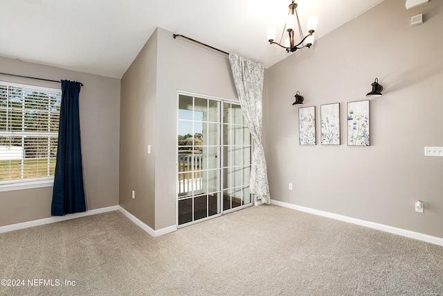 unfurnished room with carpet, a chandelier, and lofted ceiling