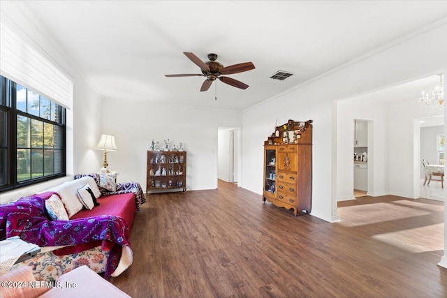 living room featuring dark hardwood / wood-style floors, crown molding, and ceiling fan with notable chandelier