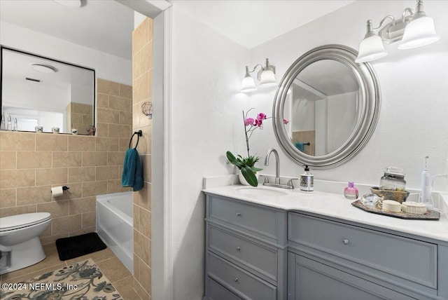 bathroom featuring vanity, a bathtub, tile patterned flooring, toilet, and tile walls