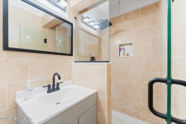 bathroom featuring tiled shower, tile walls, and vanity