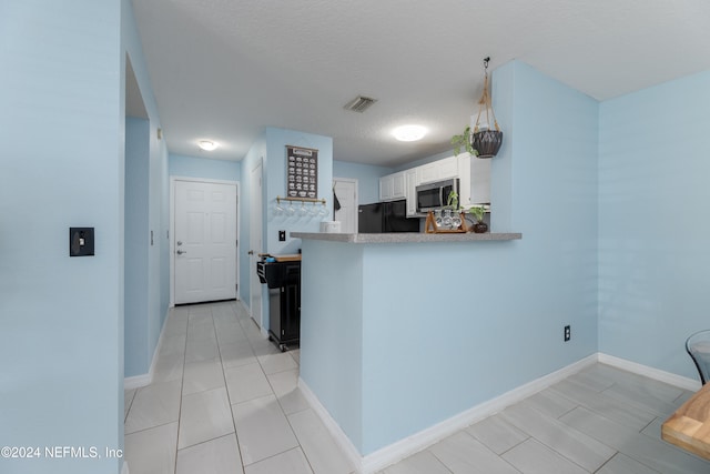 kitchen with black refrigerator, kitchen peninsula, a textured ceiling, tasteful backsplash, and white cabinetry