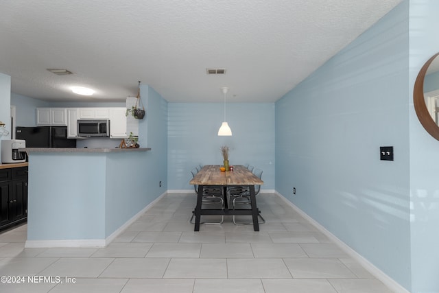 tiled dining room featuring a textured ceiling