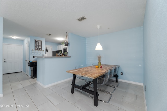 dining area with a textured ceiling and light tile patterned flooring