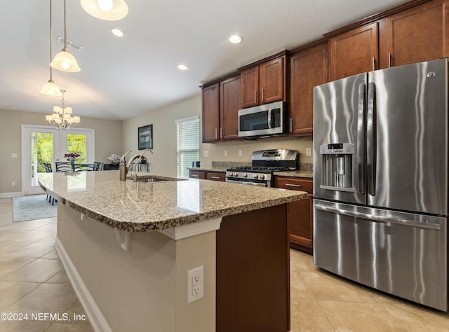 kitchen featuring appliances with stainless steel finishes, sink, decorative light fixtures, a center island with sink, and a chandelier