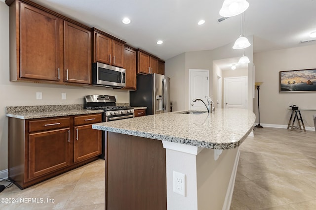 kitchen featuring sink, stainless steel appliances, light stone counters, pendant lighting, and a center island with sink