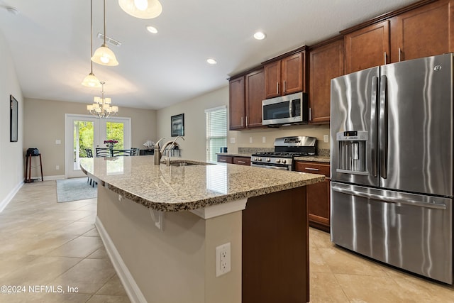 kitchen with a kitchen island with sink, sink, decorative light fixtures, appliances with stainless steel finishes, and a notable chandelier