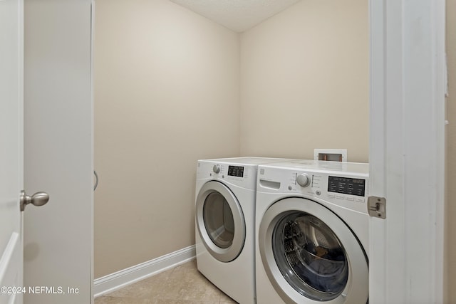 washroom with light tile patterned floors, a textured ceiling, and independent washer and dryer