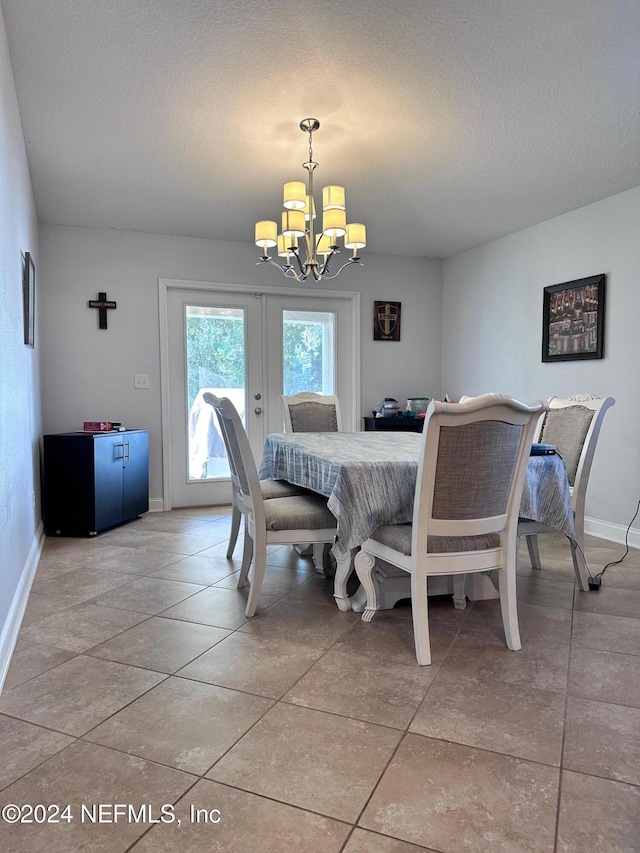 dining room with light tile patterned floors, a textured ceiling, an inviting chandelier, and french doors