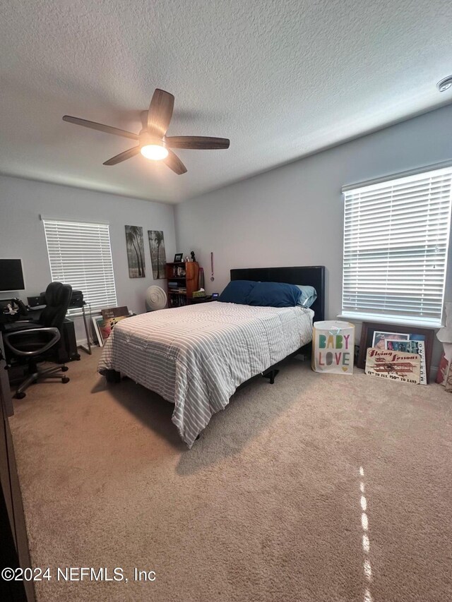 carpeted bedroom with ceiling fan and a textured ceiling