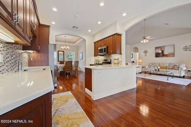 kitchen featuring sink, stainless steel appliances, tasteful backsplash, dark hardwood / wood-style flooring, and kitchen peninsula