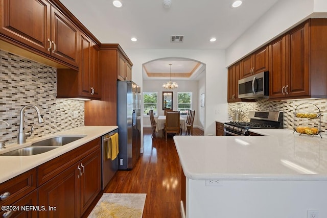 kitchen with appliances with stainless steel finishes, tasteful backsplash, sink, an inviting chandelier, and dark hardwood / wood-style floors