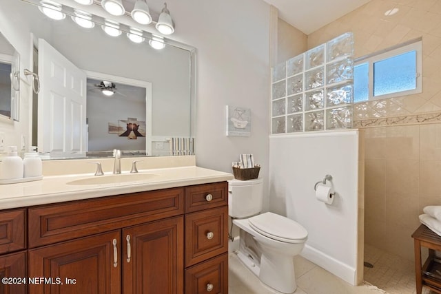 bathroom featuring vanity, ceiling fan, tiled shower, tile patterned flooring, and toilet