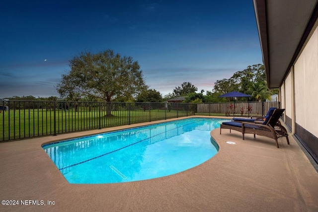 pool at dusk with a lawn and a patio area