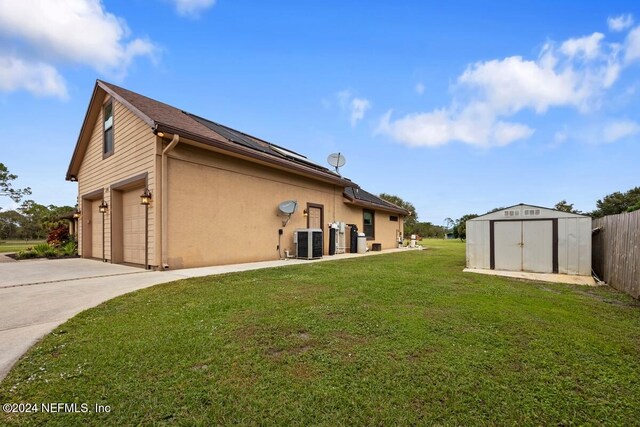 view of property exterior featuring a storage unit, a garage, a yard, and central AC