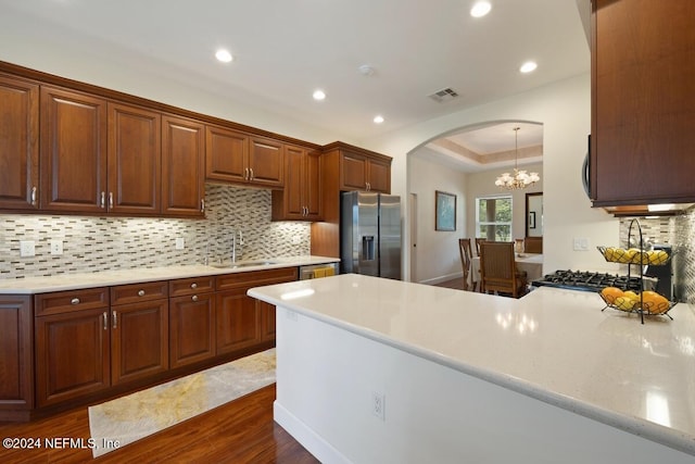 kitchen featuring decorative backsplash, appliances with stainless steel finishes, dark hardwood / wood-style flooring, sink, and an inviting chandelier