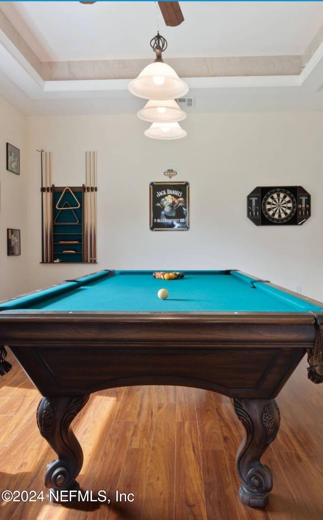 game room with wood-type flooring and a tray ceiling