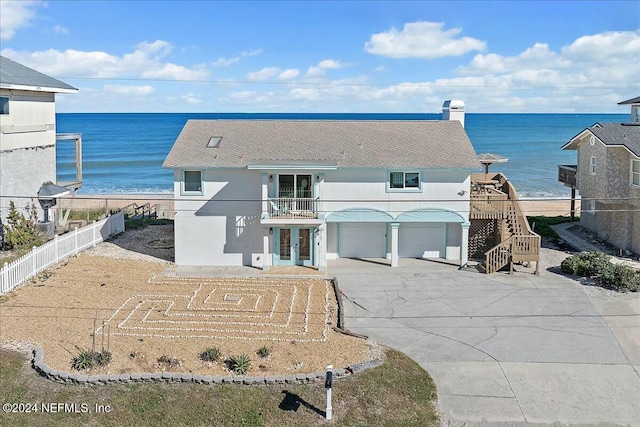 exterior space with a garage, a water view, a balcony, and french doors