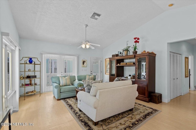 living room featuring a textured ceiling, ceiling fan, light hardwood / wood-style floors, and lofted ceiling