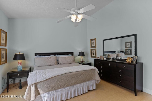 bedroom with a textured ceiling, ceiling fan, light hardwood / wood-style flooring, and lofted ceiling