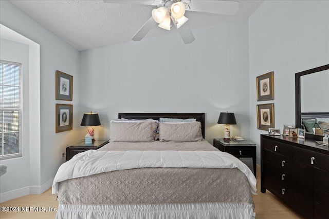 bedroom with ceiling fan, light wood-type flooring, a textured ceiling, and vaulted ceiling