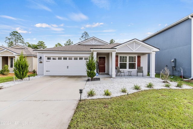 view of front of property featuring a front lawn, covered porch, and a garage